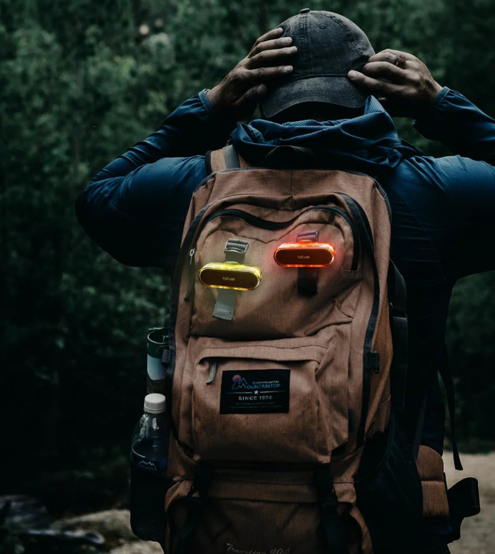 Person wearing a brown backpack with glowing lights in a forest setting